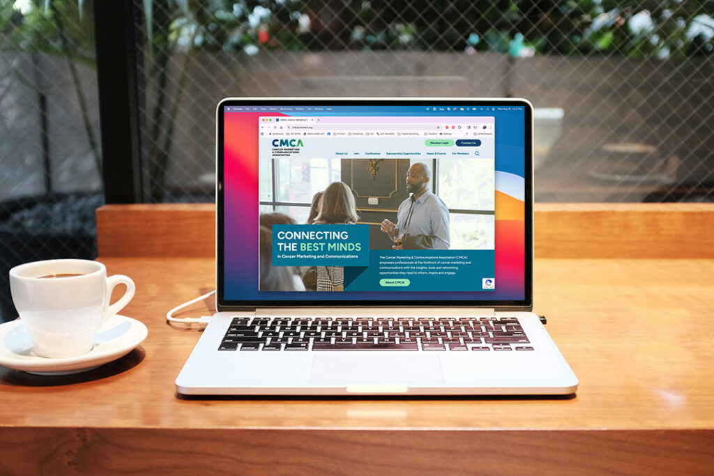 A laptop on a wooden table displays a website about networking and communications; a cup of coffee sits to the left.